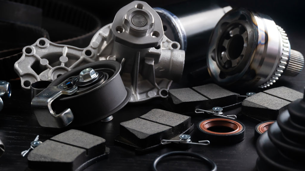 Aile de voiture cabossée posée sur établi avec pièce de remplacement neuve à côté